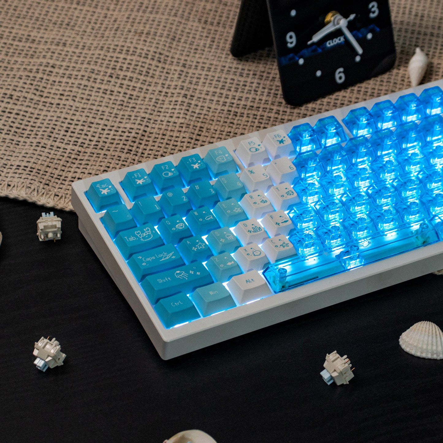 Mechanical keyboard with blue and white keys on a dark surface, surrounded by keycaps.