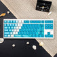 Keyboard with blue and white keys on a textured surface with shells and a clock.
