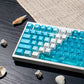 Custom Cherry profile Deep Sea Blue keycaps with a clear blue PC chassis keyboard by Taptempo, high-value mechanical keyboard setup shipping to US and EU.