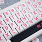 Close-up of a keyboard with pink lettering on white keys
