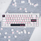 Keyboard with pink lettering on a gray surface with scattered keycaps.